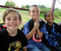 Three happy kids in front of green field